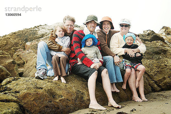 Porträt einer Familie  die auf einem Felsen gegen den Himmel sitzt