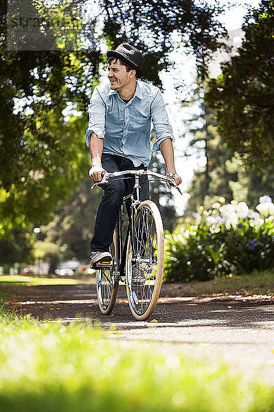 Glücklicher Mann fährt Fahrrad im Park