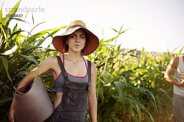Porträt einer Frau  die einen Korb trägt  während sie auf einem Bauernhof steht
