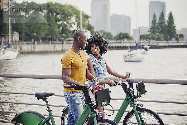 Paar mit Fahrrädern zu Fuß an der Reling gegen den Fluss
