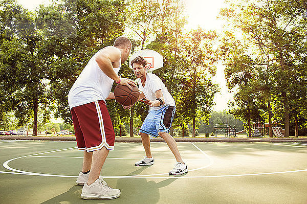 Freunde spielen Basketball auf dem Platz im Park