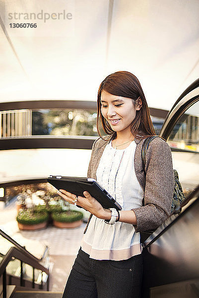 Frau benutzt Tablet-Computer auf der Rolltreppe