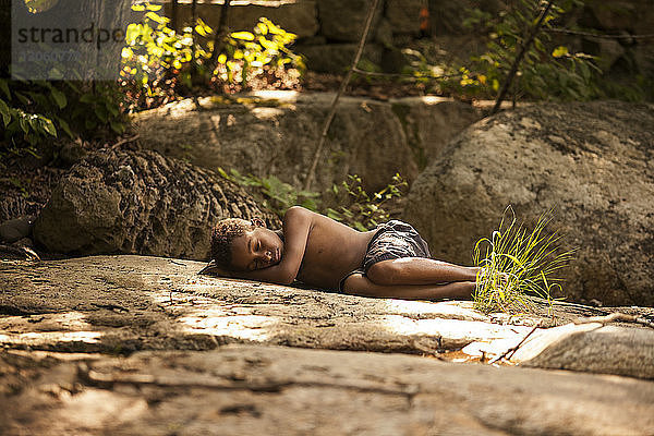 Junge schläft auf Felsen im Wald