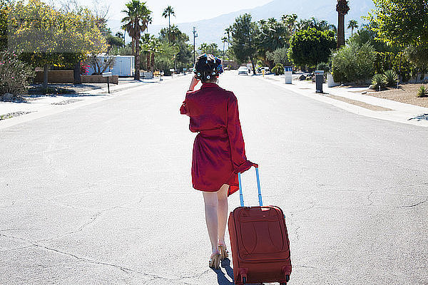 Rückansicht einer Frau mit Koffer auf der Straße