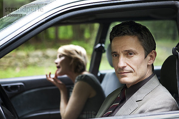 Mann schaut weg  während Frau Lippenstift im Auto anpasst
