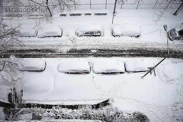 Draufsicht auf schneebedeckte Autos  die auf der Stadtstraße geparkt sind