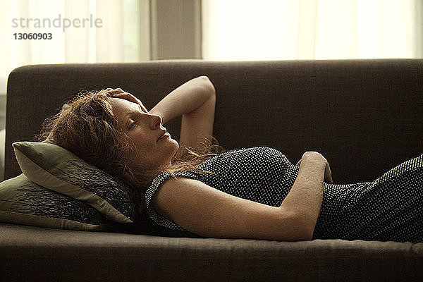 Seitenansicht einer Frau  die sich zu Hause auf dem Sofa entspannt