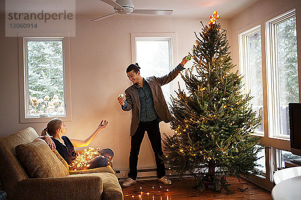 Mann und Frau schmücken den Weihnachtsbaum zu Hause