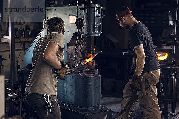 Schmied  der in der Werkstatt an der Schmiedestange in der Maschine steht