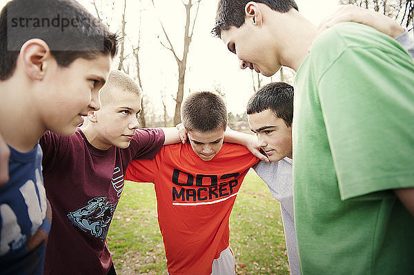 Jungen bilden Huddle  während sie im Spiel auf dem Feld stehen