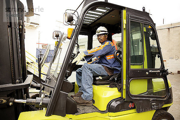 Seitenansicht eines männlichen Arbeiters beim Gabelstaplerfahren in einer Recycling-Anlage