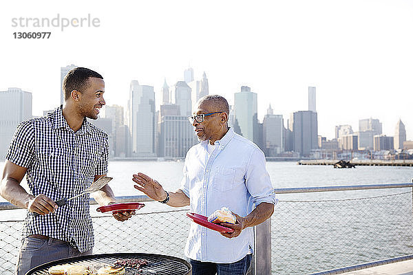 Glücklicher Sohn und Vater unterhalten sich beim Zubereiten von Essen am East River in der Stadt