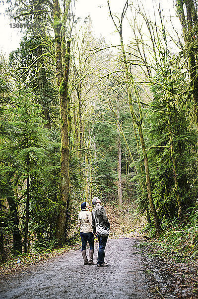 Ehepaar schaut auf  während es im Wald auf der Straße steht