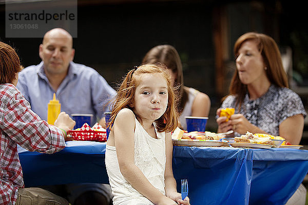 Porträt eines Mädchens  das mit seiner Familie am Picknicktisch sitzt