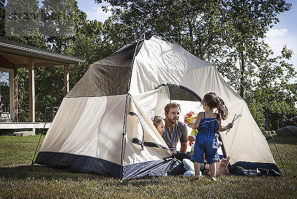 Vater mit Kindern schaut Mädchen an  während er im Zelt sitzt