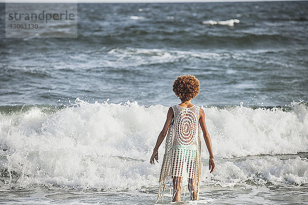 Rückansicht eines Mädchens  das an einem sonnigen Tag im Meer steht
