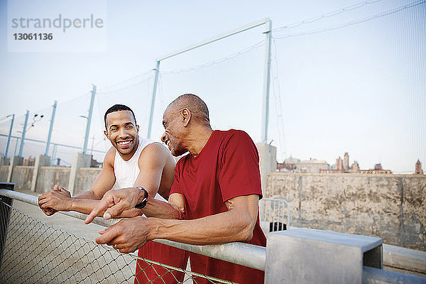 Glücklicher Vater redet mit seinem Sohn  während er am Geländer steht