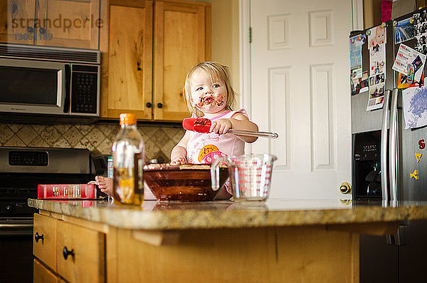 Mädchen isst Schokolade  während sie auf einer Kücheninsel sitzt