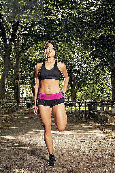 Entschlossene sportliche Frau trainiert auf Fußweg im Park