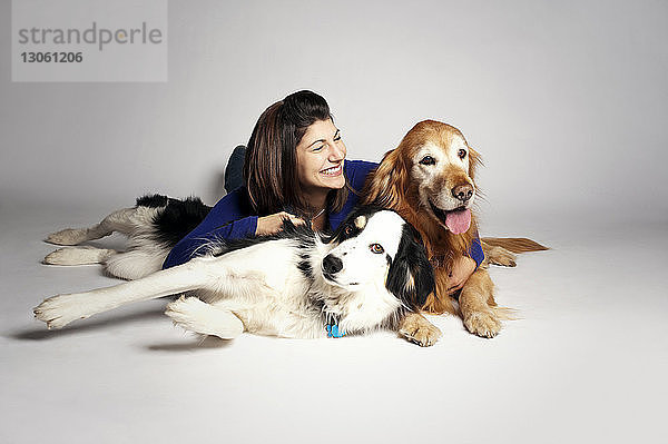 Glückliche Frau liegt mit Hunden auf weißem Hintergrund