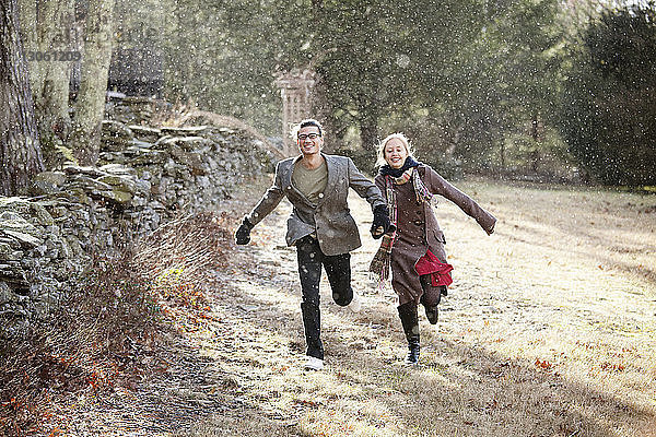 Glückliches Paar rennt im Winter auf dem Feld im Wald