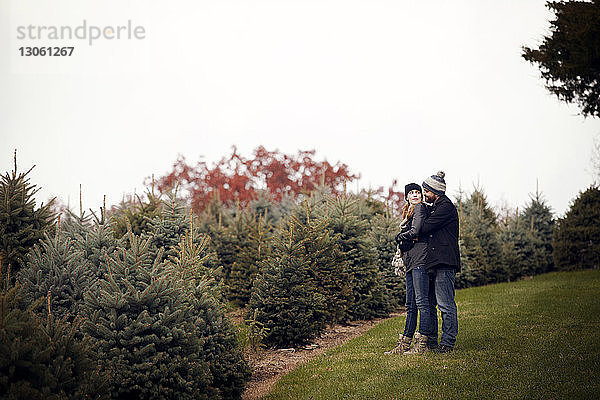 Liebespaar auf dem Feld beim Weihnachtsbaum-Bauernhof