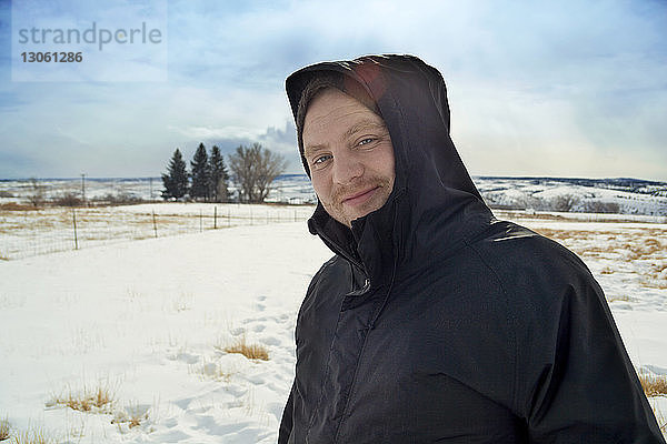 Porträt eines Mannes  der auf einem verschneiten Feld gegen den Himmel steht