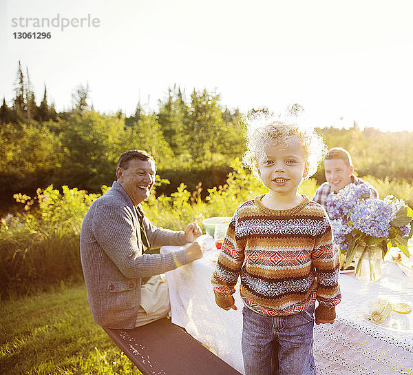 Porträt eines Jungen  der sich mit der Familie auf einem Picknicktisch vergnügt