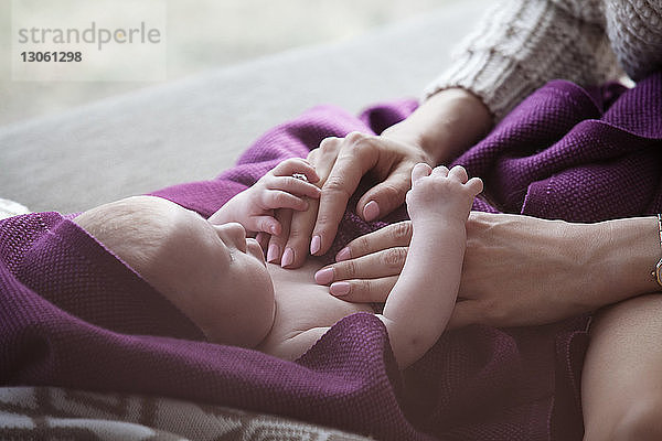 Ausgeschnittenes Bild einer Frau  die ein kleines Mädchen berührt  das zu Hause auf dem Sofa liegt