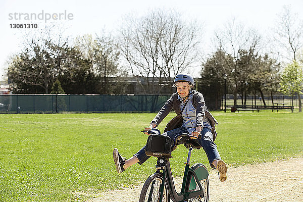 Fröhliche Frau spielt beim Fahrradfahren im Park