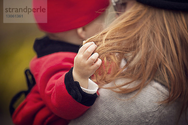 Nahaufnahme eines Mädchens  das mit den Haaren der Mutter spielt