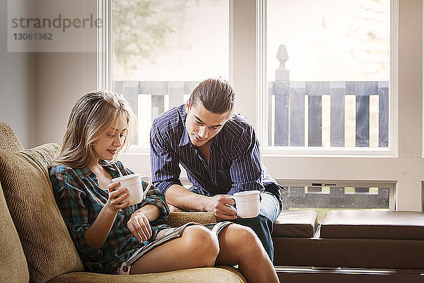 Ehepaar liest Zeitschrift beim Kaffeetrinken zu Hause