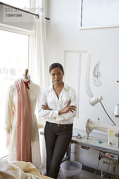 Porträt einer selbstbewussten Frau  die im Atelier neben einem Schneidermodell steht