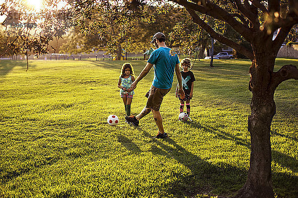Vater spielt mit Töchtern im Park Fussball