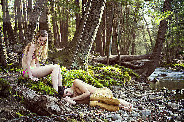 Ehepaar entspannt sich am Flussufer im Wald
