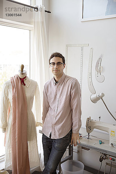 Porträt eines selbstbewussten Mannes  der im Atelier neben einem Schneidermodell steht