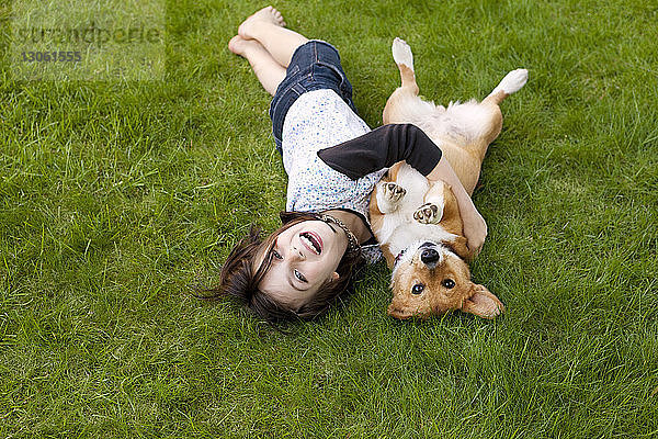 Porträt eines Mädchens beim Spielen mit Hund auf dem Feld im Hof