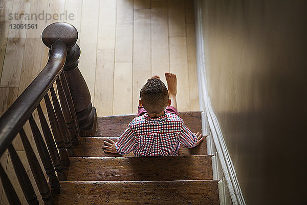 Schrägansicht eines Jungen  der zu Hause auf einer Treppe sitzt