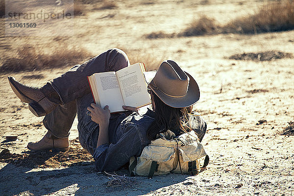 Mann liest Buch im Liegen auf dem Feld
