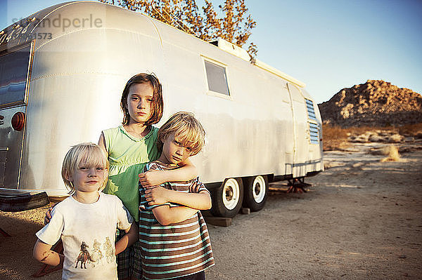 Porträt von Geschwistern  die an einem sonnigen Tag beim Wohnmobil stehen