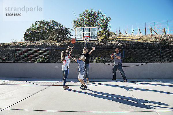 Familie spielt an einem sonnigen Tag Basketball