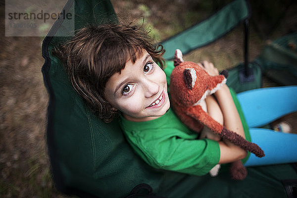 Portrait eines lächelnden Mädchens mit Spielzeug in der Hand im Wald