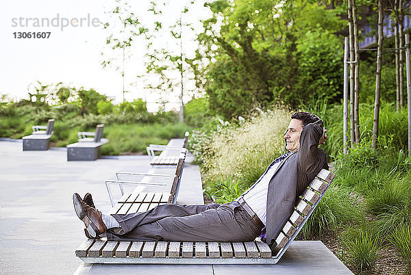 Seitenansicht eines Geschäftsmannes  der sich auf einem Liegestuhl entspannt