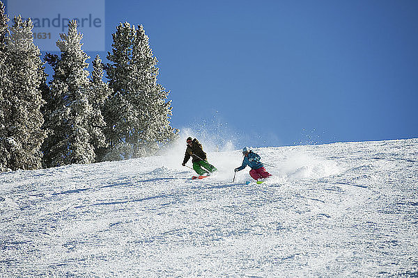 Paar Skifahren auf schneebedecktem Berg gegen Himmel