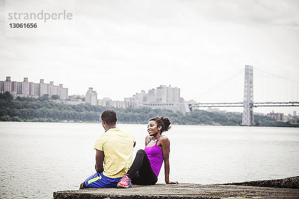 Ehepaar sitzt auf Pier am Flussufer