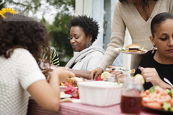 Familie und Freunde beim Essen am Picknicktisch im Hinterhof