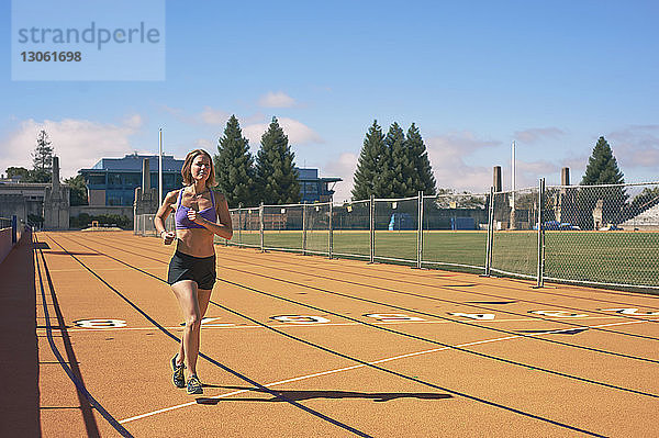 Weibliche Athletin läuft auf der Bahn gegen den Himmel