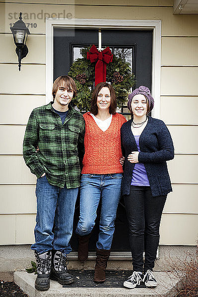 Porträt einer glücklichen Familie  die zu Weihnachten vor dem Haus steht