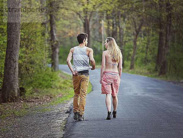 Rückansicht eines Paares  das sich beim Gehen auf der Straße unterhält