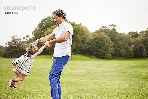Verspielter Vater schwingt Tochter  während er im Park steht